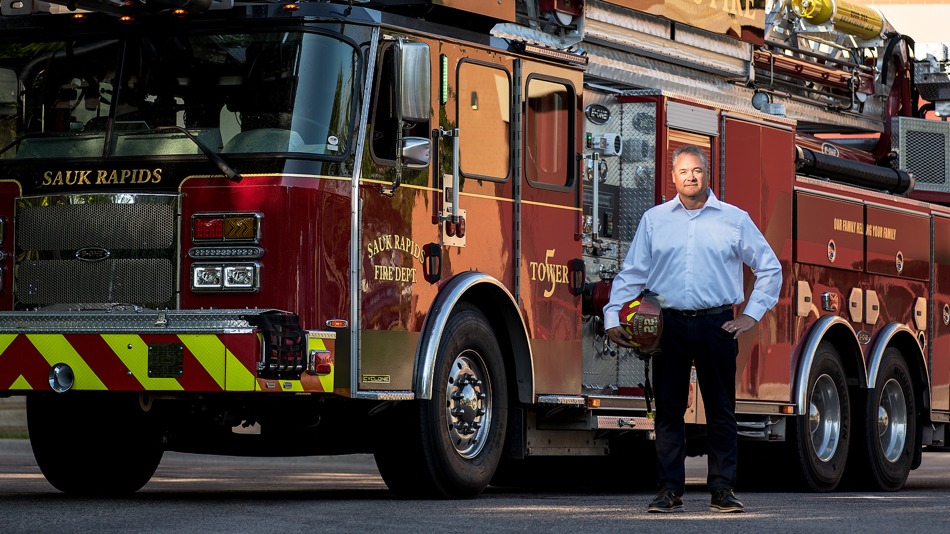 Jared Gapinski, Republican candidate for Minnesota State Senate District 13, holding a Sauk Rapids fire captain helmet in front of a firetruck
