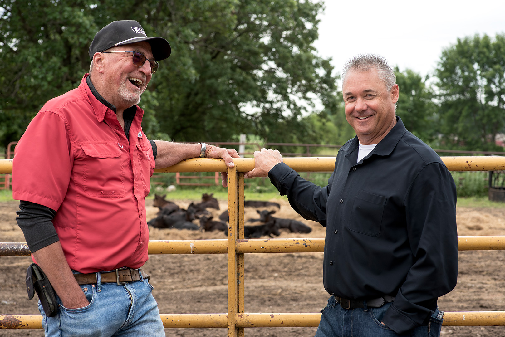 Jared Gapinski, Minnesota State Senate candidate, smiling with a constituent on a Central Minnesota farm with cattle in the background